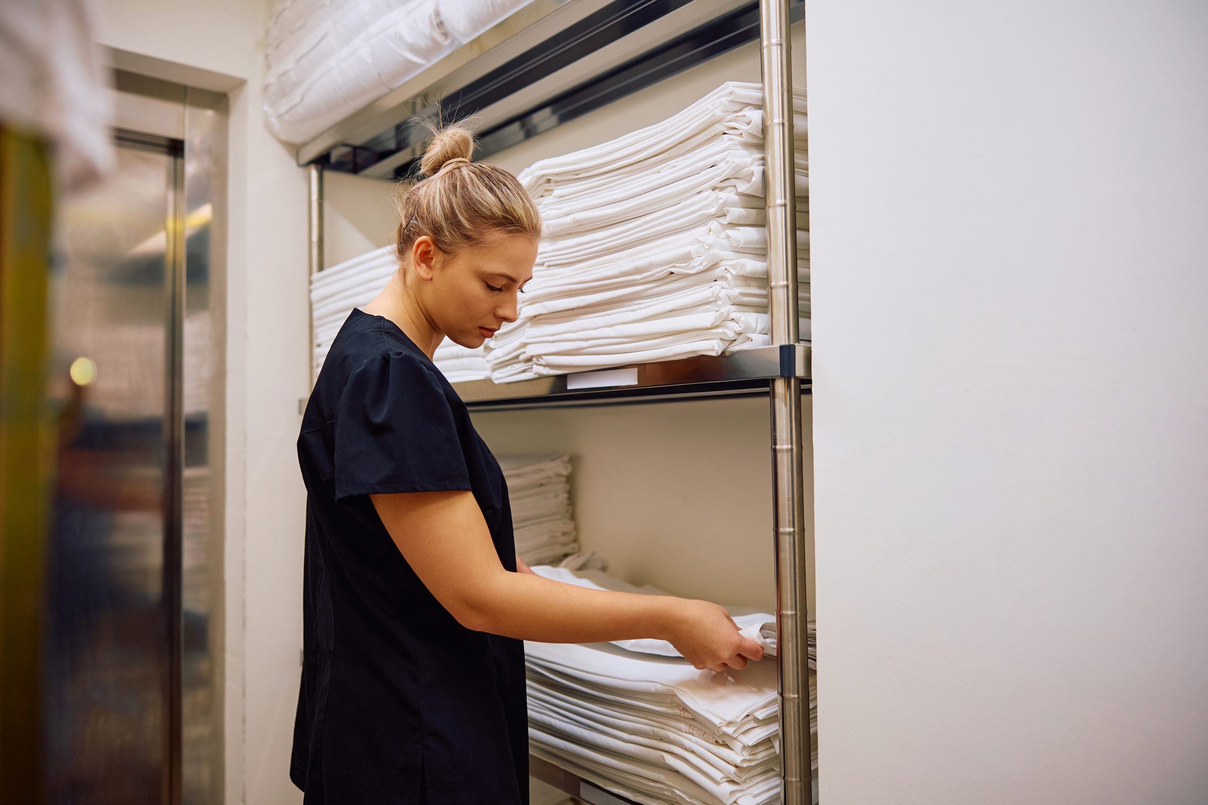 Housekeeper stocking a hotel linen room with pressed linen