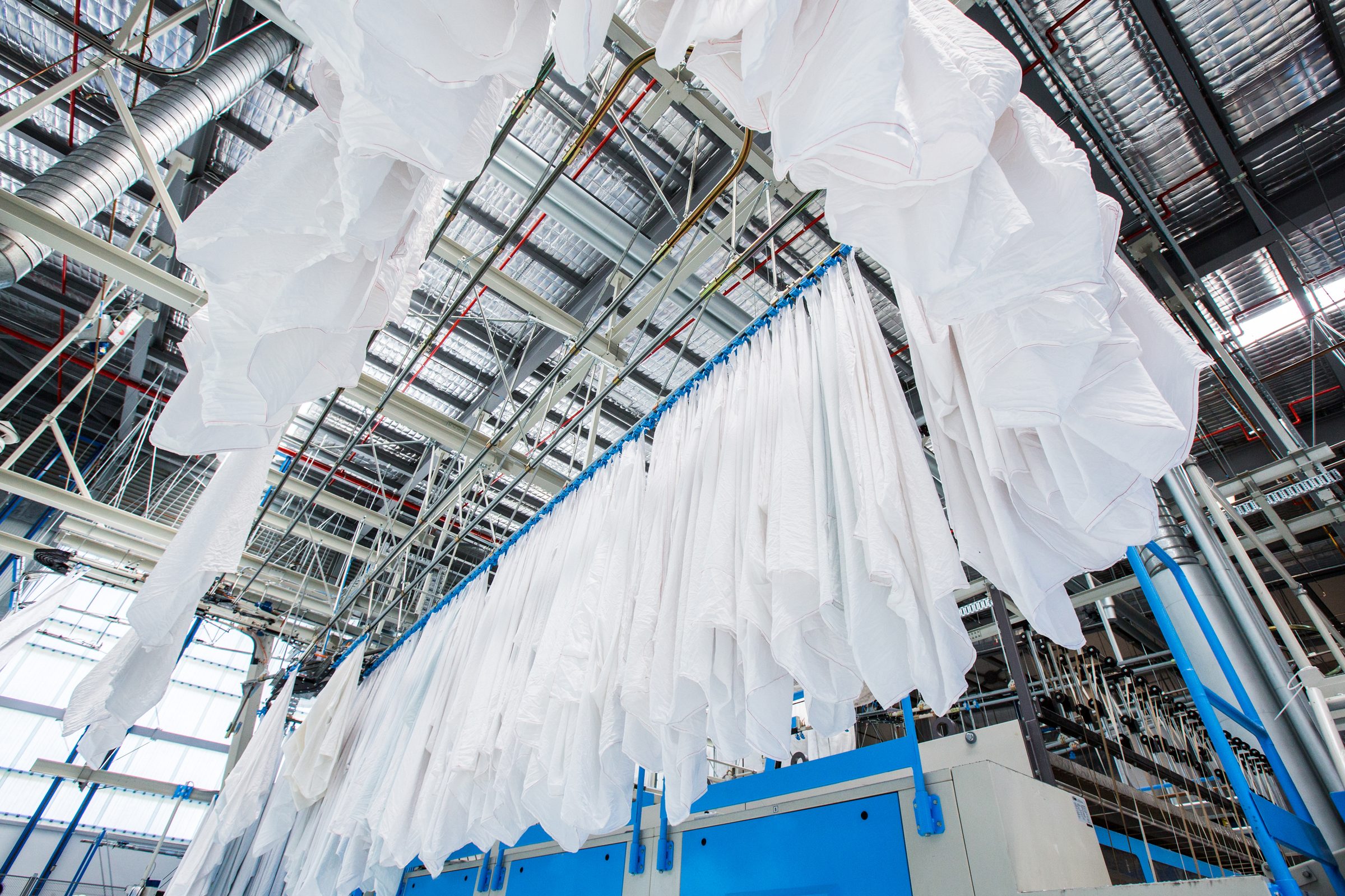 Overhead linen rail system in a commercial laundry plant